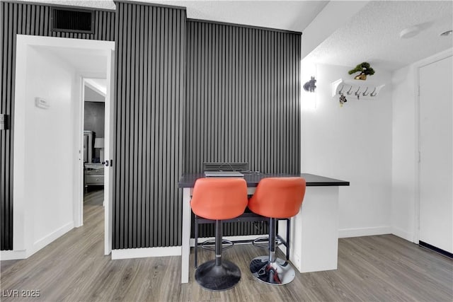 dining room with baseboards, a textured ceiling, and wood finished floors