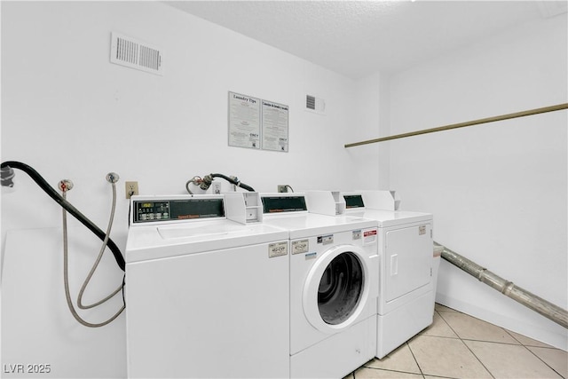 community laundry room featuring visible vents, independent washer and dryer, and light tile patterned floors