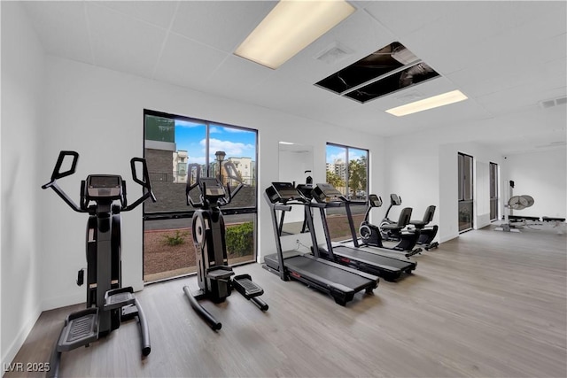 exercise room featuring baseboards, visible vents, wood finished floors, and a paneled ceiling