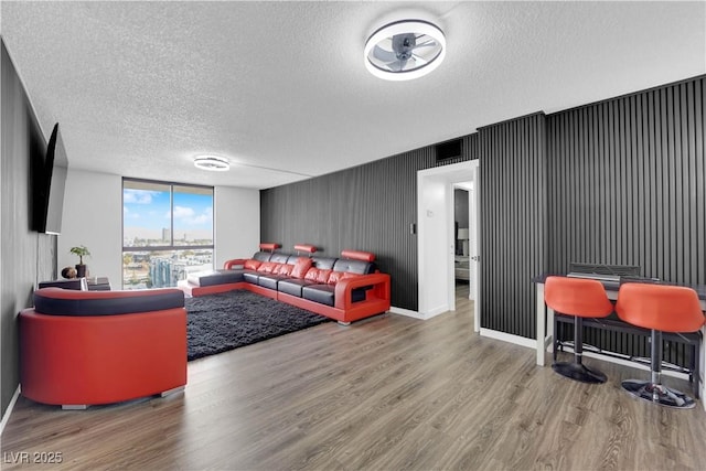 living room with baseboards, expansive windows, a textured ceiling, and wood finished floors
