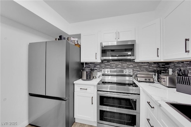 kitchen with white cabinetry, light stone counters, backsplash, and appliances with stainless steel finishes