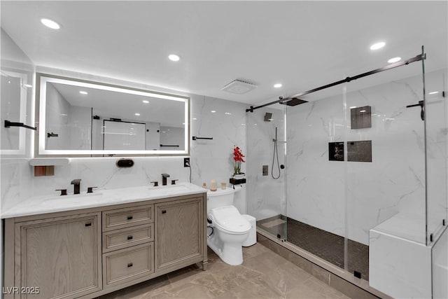 bathroom with a marble finish shower, double vanity, a sink, and toilet