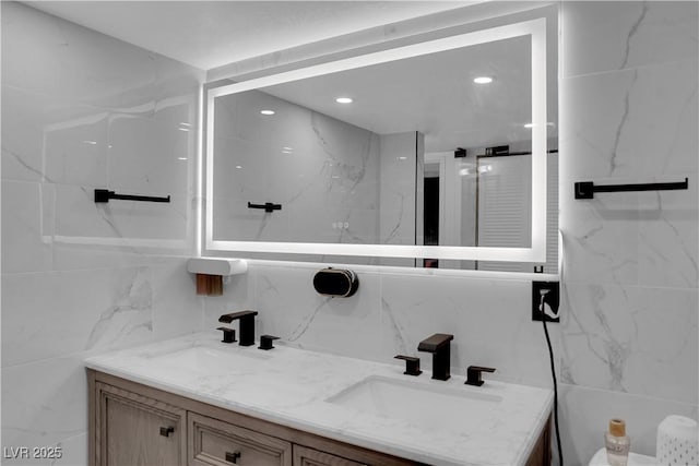 bathroom with double vanity, a sink, and tile walls