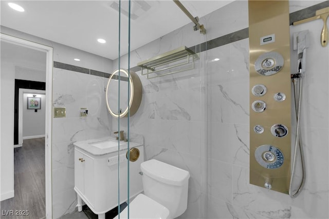 full bath with tile walls, a marble finish shower, toilet, and vanity