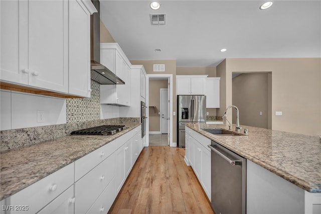 10348 Bressana Dr, Las Vegas, NV 89135 - kitchen with stainless steel appliances, a sink, white cabinetry, wall chimney exhaust hood, and decorative backsplash