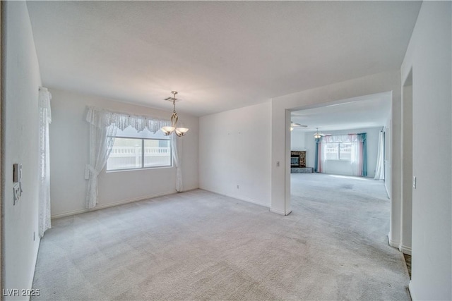 3891 Sedgwick, Pahrump, NV 89061 - spare room featuring baseboards, a fireplace with raised hearth, a chandelier, and light colored carpet