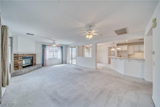 3891 Sedgwick, Pahrump, NV 89061 - unfurnished living room with visible vents, light carpet, a ceiling fan, and a stone fireplace