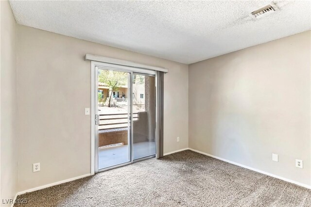 spare room with a textured ceiling, carpet, visible vents, and baseboards