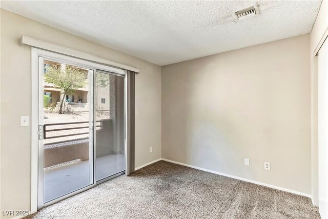 carpeted spare room featuring a textured ceiling, visible vents, and baseboards