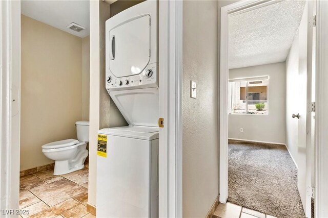 laundry room featuring baseboards, laundry area, stacked washer / drying machine, and visible vents