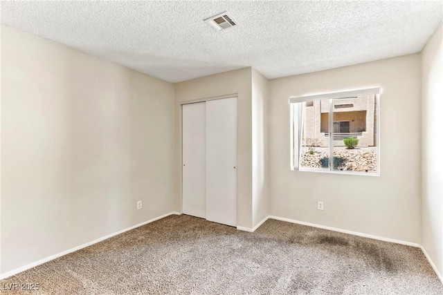 unfurnished bedroom with baseboards, visible vents, carpet floors, and a closet