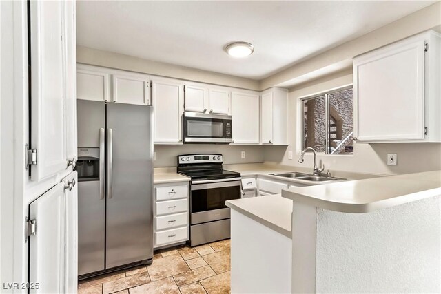kitchen with white cabinets, light countertops, a sink, a peninsula, and appliances with stainless steel finishes