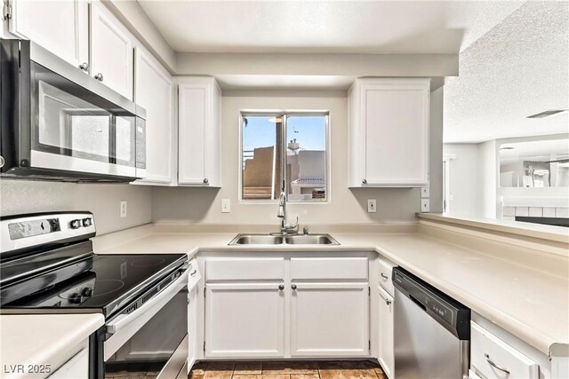 kitchen with white cabinets, appliances with stainless steel finishes, a sink, and light countertops
