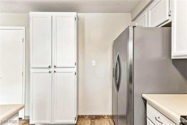 kitchen featuring white cabinets, baseboards, light countertops, and freestanding refrigerator