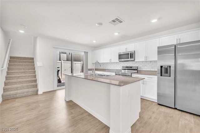 6952 Crimson Shadow St, North Las Vegas, NV 89086 - kitchen with appliances with stainless steel finishes, a sink, a kitchen island with sink, light wood-style floors, and white cabinetry