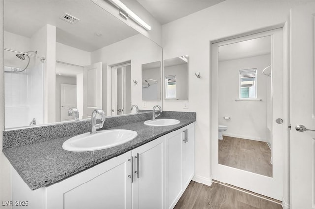 full bathroom with wood finished floors, toilet, double vanity, and baseboards