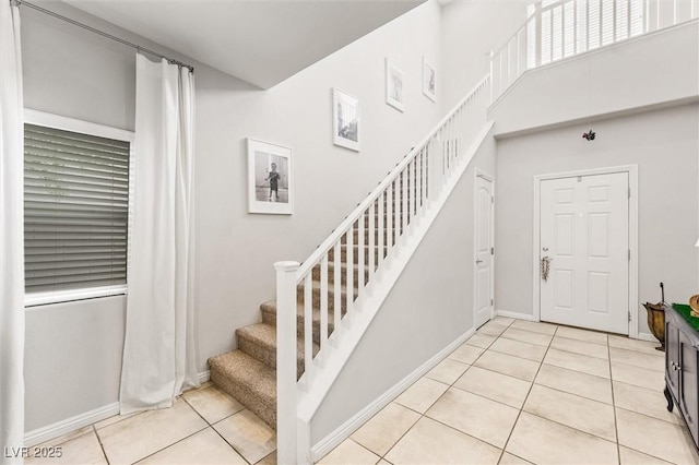 staircase with baseboards, a towering ceiling, and tile patterned flooring