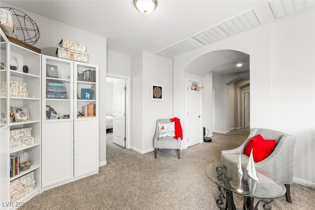 sitting room with carpet floors, arched walkways, and baseboards