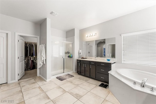 full bathroom with tile patterned flooring, a shower stall, vanity, a garden tub, and a spacious closet
