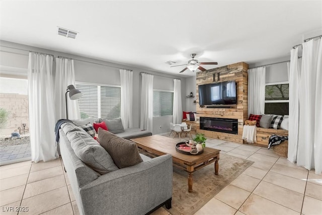 living room with a ceiling fan, light tile patterned floors, a fireplace, and visible vents