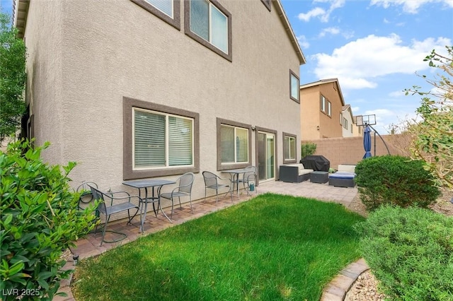 back of property with stucco siding, fence, an outdoor living space, a yard, and a patio area