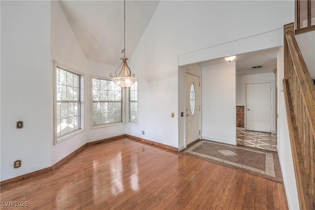 interior space featuring baseboards, high vaulted ceiling, an inviting chandelier, and wood-type flooring