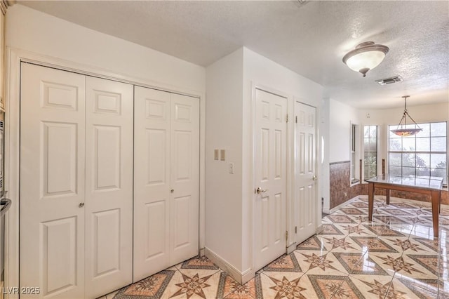 interior space featuring baseboards, a textured ceiling, and visible vents