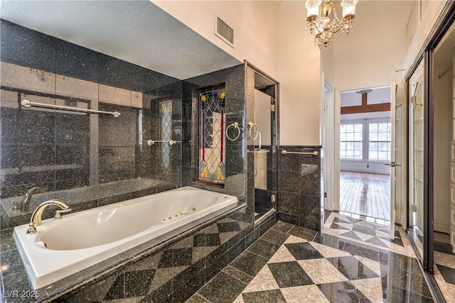 full bath featuring a tub with jets, granite finish floor, visible vents, and tile walls