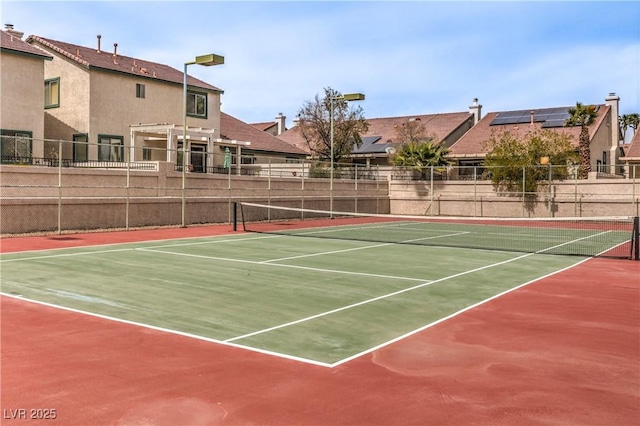view of tennis court featuring community basketball court and fence