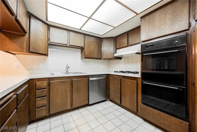 kitchen featuring stainless steel dishwasher, dobule oven black, a sink, light countertops, and under cabinet range hood