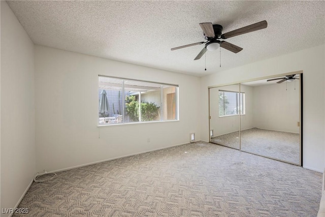unfurnished bedroom featuring a ceiling fan, a textured ceiling, a closet, and carpet