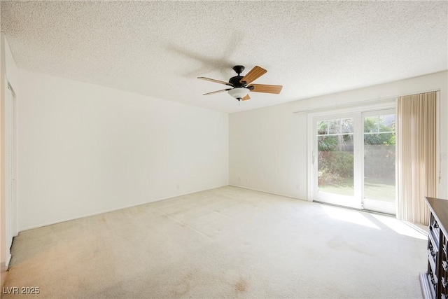 spare room with light colored carpet, ceiling fan, and a textured ceiling