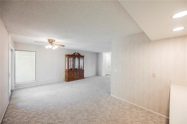 spare room with carpet, a ceiling fan, baseboards, and a textured ceiling
