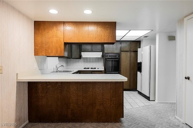 kitchen featuring white refrigerator with ice dispenser, light countertops, oven, a sink, and a peninsula