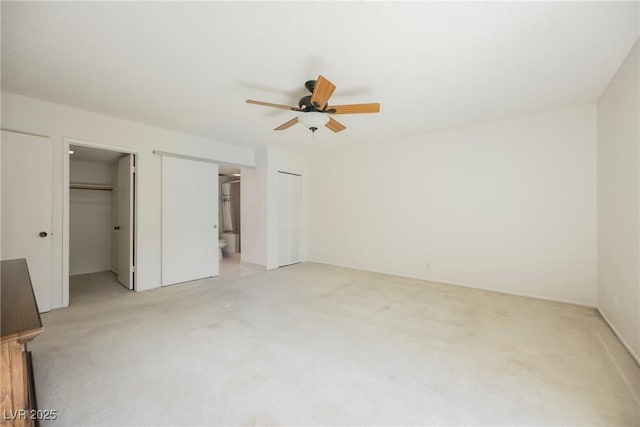 unfurnished bedroom with a closet, a walk in closet, light colored carpet, and ensuite bathroom