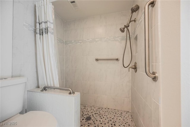 full bathroom with toilet, a tile shower, and visible vents