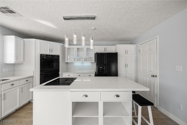 861 Mcmurray Dr, Pahrump, NV 89060 - kitchen with white cabinetry, light wood-style flooring, black appliances, and visible vents
