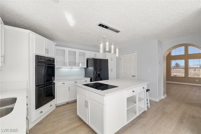 861 Mcmurray Dr, Pahrump, NV 89060 - kitchen with arched walkways, open shelves, light wood-style floors, black appliances, and a center island