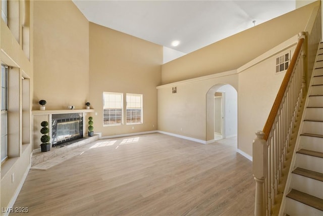 861 Mcmurray Dr, Pahrump, NV 89060 - unfurnished living room featuring light wood-style floors, stairway, a high ceiling, a glass covered fireplace, and arched walkways