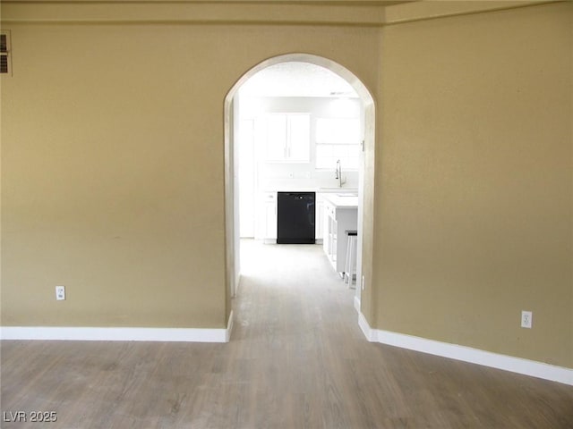 861 Mcmurray Dr, Pahrump, NV 89060 - hallway with arched walkways, baseboards, a sink, and wood finished floors
