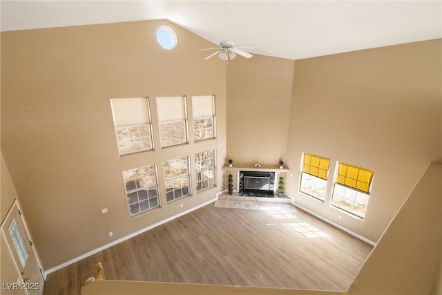 861 Mcmurray Dr, Pahrump, NV 89060 - unfurnished living room featuring high vaulted ceiling, baseboards, ceiling fan, a glass covered fireplace, and wood finished floors