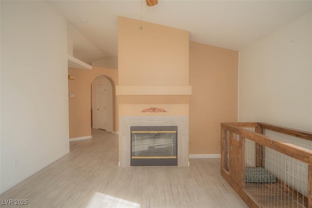 9323 W Rochelle Ave, Las Vegas, NV 89147 - living area with arched walkways, a glass covered fireplace, wood finished floors, baseboards, and vaulted ceiling