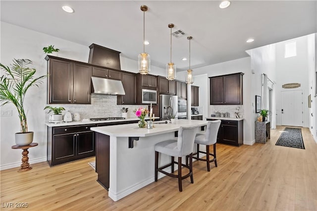 11834 Albissola Ave, Las Vegas, NV 89138 - kitchen with light countertops, light wood-style flooring, appliances with stainless steel finishes, under cabinet range hood, and a breakfast bar area