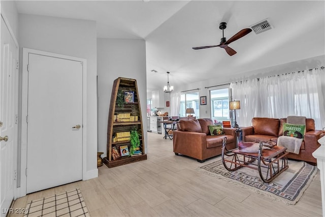 living room with vaulted ceiling, ceiling fan with notable chandelier, and visible vents