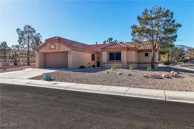 mediterranean / spanish home with an attached garage, stucco siding, a tiled roof, and driveway