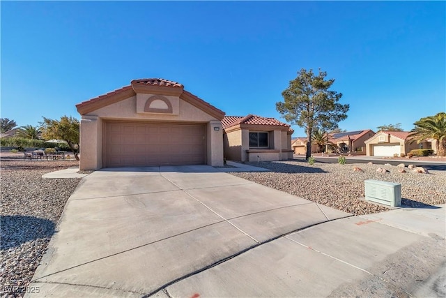 mediterranean / spanish-style home featuring concrete driveway, stucco siding, a tile roof, and an attached garage
