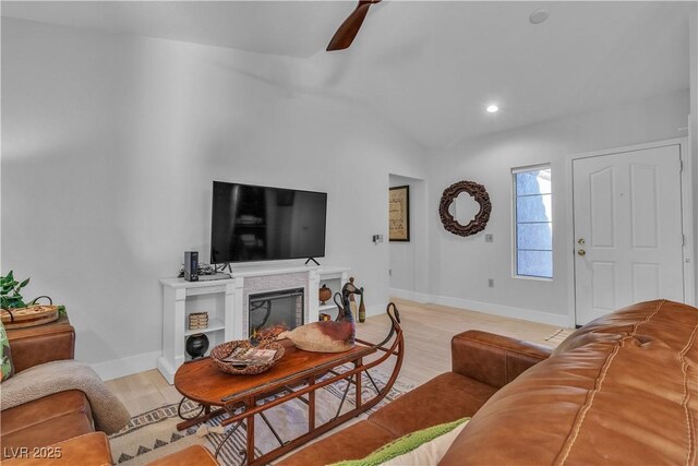 living room featuring baseboards, vaulted ceiling, a fireplace, and a ceiling fan