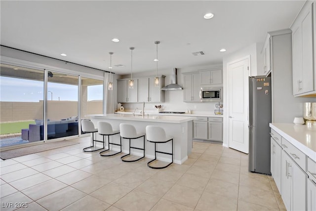 8564 Scalpay St, Las Vegas, NV 89166 - kitchen featuring wall chimney exhaust hood, stainless steel appliances, a kitchen bar, light countertops, and recessed lighting