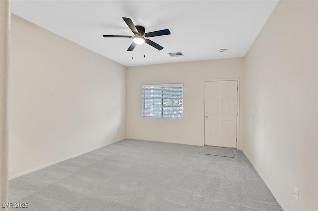 spare room featuring light colored carpet, visible vents, and a ceiling fan