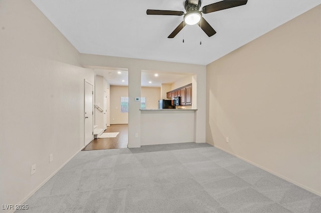 unfurnished living room with a ceiling fan, baseboards, recessed lighting, and light carpet